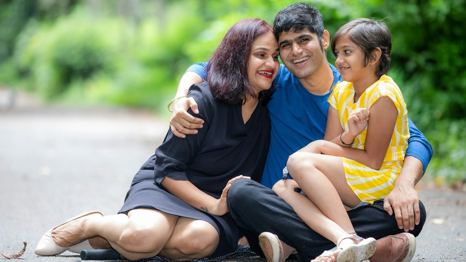 Un couple souriant avec leur enfant, assis ensemble à l'extérieur